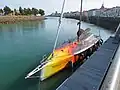un bateau amarré, sa coque est noire à l’arrière et jaune/orange à l’avant, avec des motifs de lave volcanique