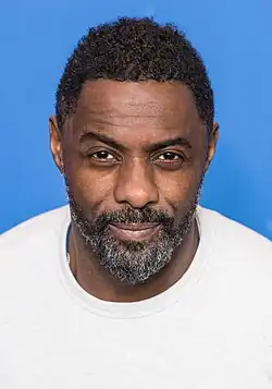 Photo en buste d'un homme au cheveux noirs et courts avec une barbe grisonnante.