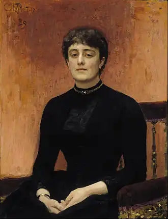 Portrait d'une femme assise, habillée en noir, de face.