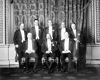 Groupe de huit hommes en costume de soirée. Le roi est assis au milieu entouré par ses premiers ministres.