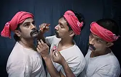 "Photographie de trois acteurs, dont l'un maquille le visage d'un autre."