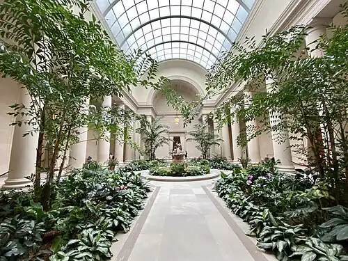 Cour intérieure avec colonnes toscanes et parterres de plantation symétriques.