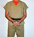 Détenu dans des menottes articulées attachées à une ceinture en cuir