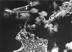 Photo aérienne noir et blanc montrant un bombardier et des colonnes de fumées venant du sol