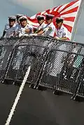 Membres d'équipage du navire destroyer JS Kongō, devant le drapeau de la Force maritime d'autodéfense japonaise.
