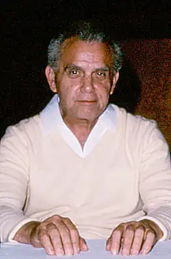 photographie en couleur d'un homme âgé assis devant une table