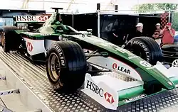 Photographie d'une Formule 1 vert foncé et blanche, vue de trois-quarts, en exposition.