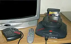 Cartouche de jeu noire insérée dans une console noire. La console est posée sur une table à côté d'une télévision.