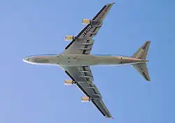 Vue de dessous d'un 747 en vol. Sous chacune des deux ailes se trouvent deux moteurs.