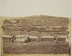 Flanc d'une colline aride recouverte de tranchées et de sacs de sables
