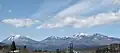 Vue panoramique d'une chaîne de montagnes sous un ciel bleu nuageux.