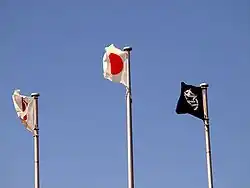 Trois drapeaux flottent dans le ciel.