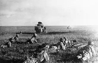 Photo en noir et blanc de soldats allongés tirant au fusil.