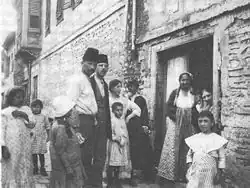 photographie noir et blanc: deux hommes en fez, plusieurs femmes et enfants