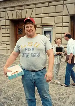 photo d'un homme souriant portant jean, tee-shirt et casquette.