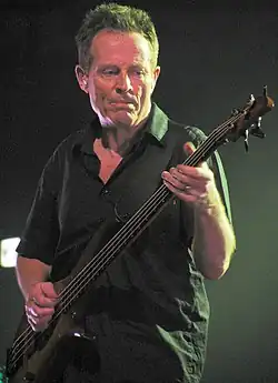 photo d'un homme en polo noir jouant de la basse.