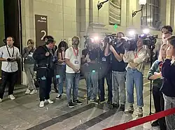 Photographie en couleurs représentant un groupe de personnes (journalistes) dans la salle des pas perdus du tribunal de Pau.