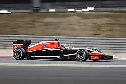 Photo de profil droit d'une monoplace rouge aux flancs noirs, sur un circuit, en nocturne