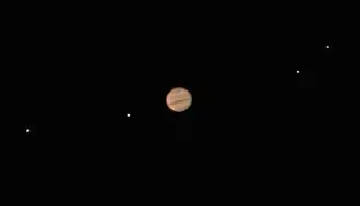 Jupiter est reconnaissable avec ses bandes rouges. Les lunes sont distinguable et non floues mais apparaissent comme des points lumineux.