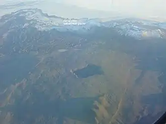 Vue aérienne en direction du sud de l'extrémité occidentale du front glaciaire du Dyngjujökull avec la Kistufell enneigée à droite et le cratère du Urðarháls au premier plan avec à sa gauche le Holuhraun et à sa droite le Dyngjuháls.