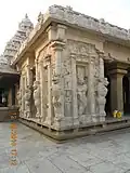 Depuis la cour, le mandapa isolé, rattaché tardivement au temple par une autre salle. Angle : lion et porteuse de chasse-mouches, gardien. Grès couvert d'un enduit blanc, tardif