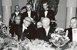 Photographie de plusieurs hommes en tenue de soirée assis lors d'un banquet