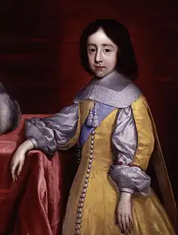 Portrait d'un garçon au cheveux noirs mi-longs portant une sorte de tunique jaune et blanche