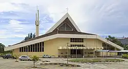 Photographie d'une cathédrale catholique de style moderne et de son parking.