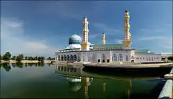 Photographie d'une mosquée bleu et blanc et de son bassin qui l'entoure.