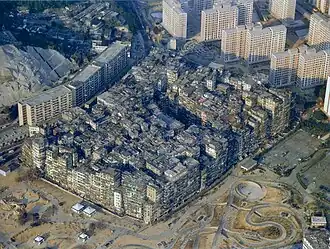Vue aérienne d'un quartier urbain constitué de grands immeubles très délabrés, entouré de grands immeubles neufs au nord et de travaux au sud.