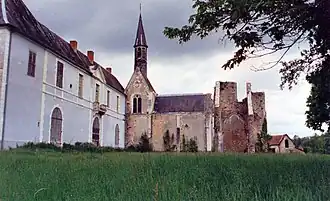 Photographie d'un monastère dont sont visibles un long mur et un clocher d'église