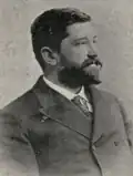 Photographie noir et blanc d'un homme en habit cravate.