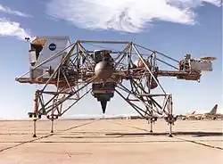 Le deuxième LLRV. À gauche, la cabine en mousse expansée devant simuler le champ de vision réduit du pilote du véritable LEM. À droite, en porte-à-faux, la nacelle contenant l'électronique de bord. Le toit de la cabine en mousse fut retiré à la suite du crash du pilote d'essai Joe Algranti le 8 décembre 1968, car il fut découvert qu'il perturbait les caractéristiques aérodynamiques de l'engin. Au centre, le turbofan CF700-2V sur cardans simulant la pesanteur lunaire.