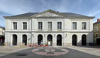 Photographie d'un bâtiment d'un étage sur rez-de-chaussée à sept hautes arcades fermées par des grilles en fer. La partie centrale, surmontée d'un fronton triangulaire, est en légère avancée.