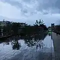Le paysage urbain se reflète dans les flaques avec le nouveau revêtement de la place.