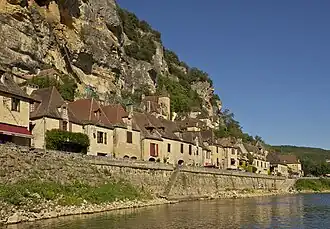 Bâtiments entre falaise et rivière.