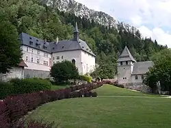 Bâtiments aux façades blanches et toits gris, avec des allées piétonnes bien entretenues, au pied d'une crête rocheuse.