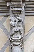 Photographie d'une sculpture sur bois, un homme buvant à même une outre.