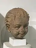 Garçon souriant. Statue en stuc de style Gandhara, réalisée entre les IIe et IIIe&nbsp;siècles.