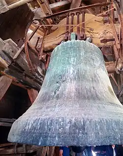 Photo de la plus grosse cloche de la cathédrale, avec son mécanisme et des éléments de charpente.