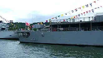 Avant-gauche d'un navire-école de guerre arborant le pavillon de la marine à sa proue.