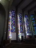 Image prise de l'intérieur de la cathédrale, centrée sur des vitraux colorés.