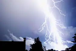 Photographie de la foudre s'abattant sur des maisons.