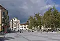 Côté sud de la place, vu vers l'ouest ; au fond, façade de l'église de la Trinité.