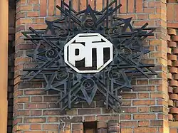 Fer forgé décoratif, peint, monogramme des PTT, sur un ancien bâtiment administratif des postes à Lille, situé près de l'arrière de l'ancienne Gare Lille-St-Sauveur/Sernam.