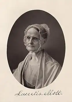 Portrait de dame, le regard direct, la tête enfermée dans un voile ou une capuche transparente.