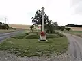 Croix de chemin, à l'arrière-plan : éoliennes.