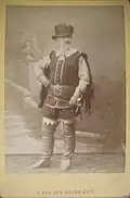 photo recto : Gally en tenue de scène soldat, devant des décors