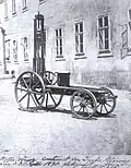 Photo d'une voiture, en apparence une planche avec quatre roues avec une potence et un siège rudimentaire.