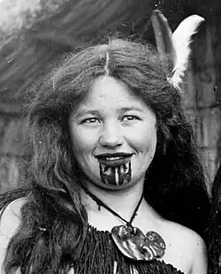 jeune Maorie tatouée au menton en tenue traditionnelle.